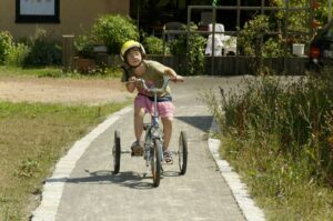 Kind mit Helm sitzend auf einem dreirädrigen Fahrrad